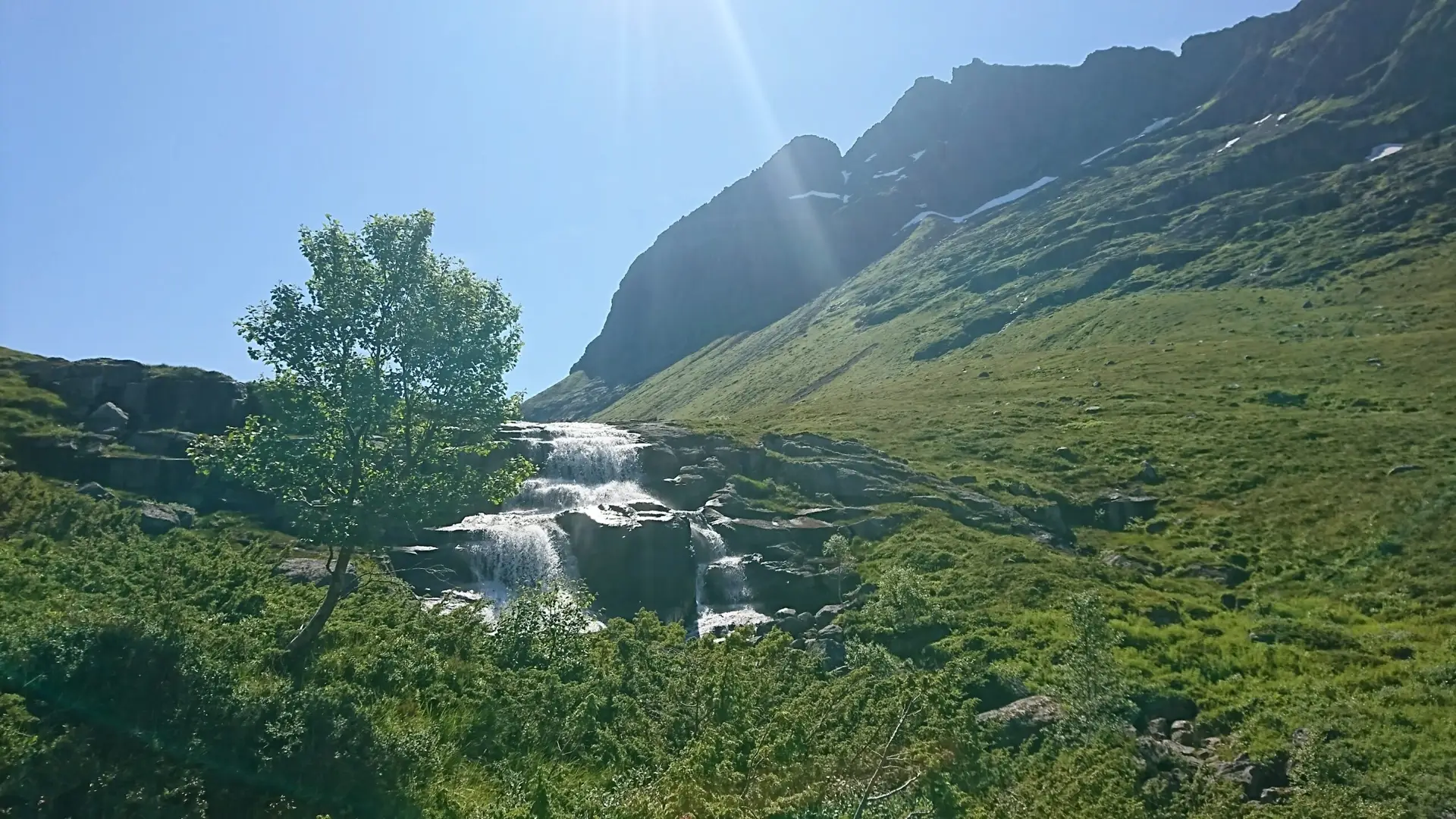 Bekken som renner nedover med himmel og fjell i bakgrunn